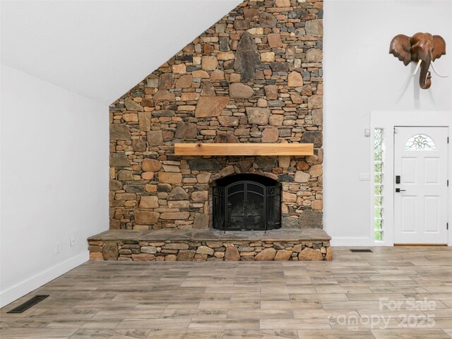 373 Vineyard Rd, Tryon, NC 28782 - unfurnished living room featuring wood finished floors, a stone fireplace, high vaulted ceiling, and baseboards