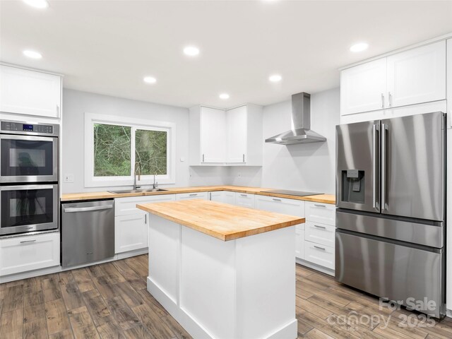 373 Vineyard Rd, Tryon, NC 28782 - kitchen featuring butcher block countertops, appliances with stainless steel finishes, wall chimney range hood, a sink, and dark wood finished floors