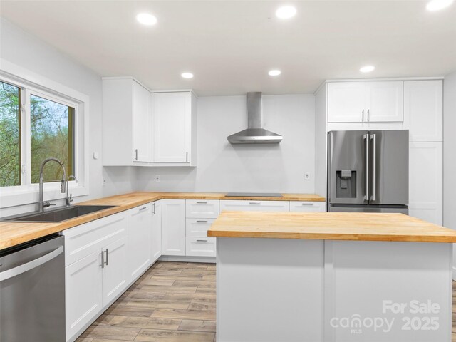 373 Vineyard Rd, Tryon, NC 28782 - kitchen with butcher block countertops, appliances with stainless steel finishes, wall chimney exhaust hood, a sink, and light wood-style flooring