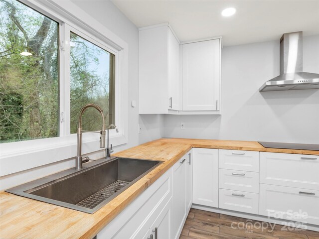 373 Vineyard Rd, Tryon, NC 28782 - kitchen with wooden counters, wall chimney range hood, a sink, black electric cooktop, and white cabinets