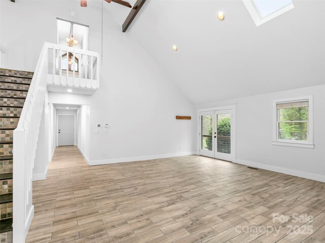 373 Vineyard Rd, Tryon, NC 28782 - unfurnished living room featuring high vaulted ceiling, stairs, a skylight, light wood finished floors, and baseboards