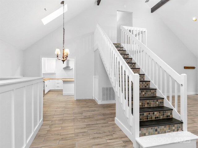 373 Vineyard Rd, Tryon, NC 28782 - stairway with a skylight, wood finished floors, high vaulted ceiling, a chandelier, and beamed ceiling