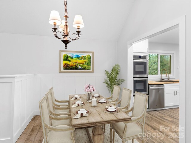 373 Vineyard Rd, Tryon, NC 28782 - dining room with light wood-style floors, a chandelier, wainscoting, lofted ceiling, and a decorative wall