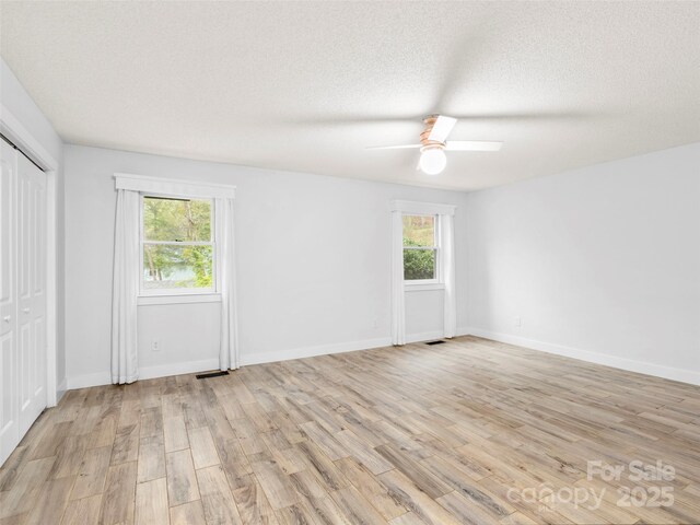 373 Vineyard Rd, Tryon, NC 28782 - unfurnished bedroom with multiple windows, light wood-style flooring, a textured ceiling, and a ceiling fan
