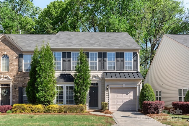 colonial house with a standing seam roof, metal roof, a garage, brick siding, and driveway