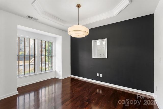 spare room with a tray ceiling, wood finished floors, ornamental molding, and visible vents