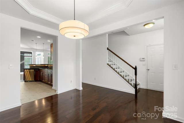 interior space with baseboards, ornamental molding, stairway, a sink, and wood finished floors