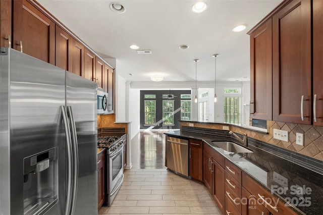 kitchen with a sink, appliances with stainless steel finishes, recessed lighting, dark stone counters, and backsplash