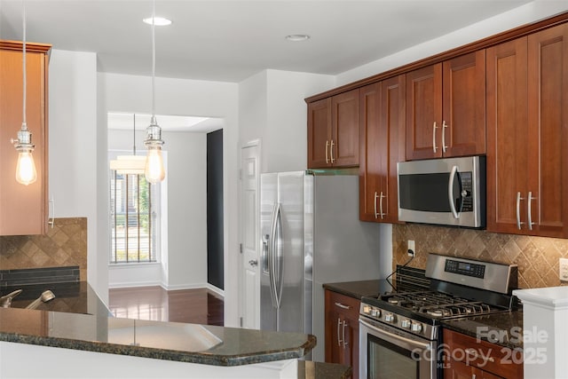 kitchen with tasteful backsplash, dark stone countertops, baseboards, decorative light fixtures, and stainless steel appliances