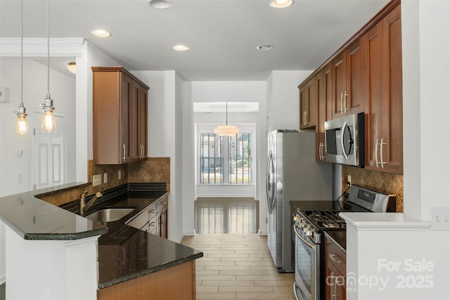 kitchen featuring dark stone countertops, backsplash, light wood-style floors, stainless steel appliances, and a sink
