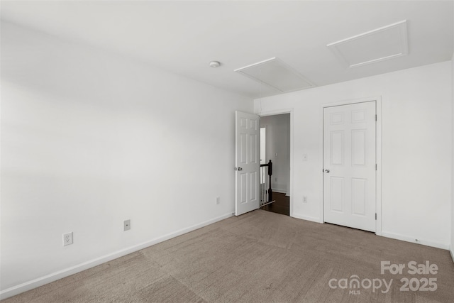 unfurnished bedroom with carpet, baseboards, and attic access