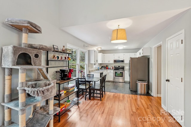 kitchen with light countertops, light wood finished floors, appliances with stainless steel finishes, white cabinetry, and a sink