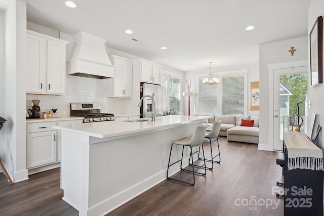 kitchen with a sink, stainless steel appliances, light countertops, premium range hood, and dark wood-style flooring