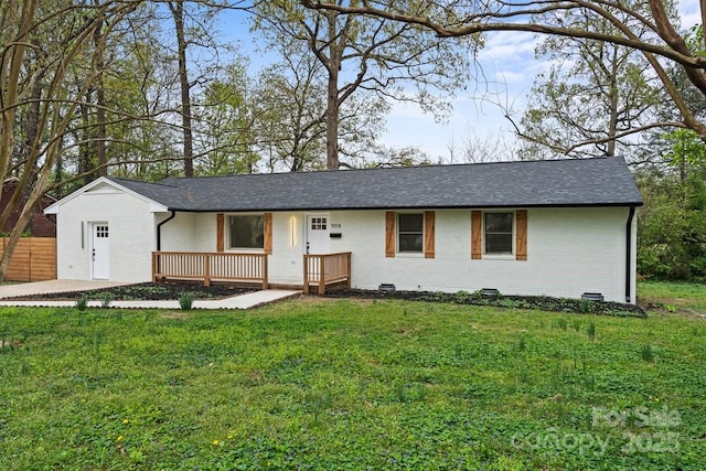 ranch-style house featuring brick siding, roof with shingles, a front yard, and fence