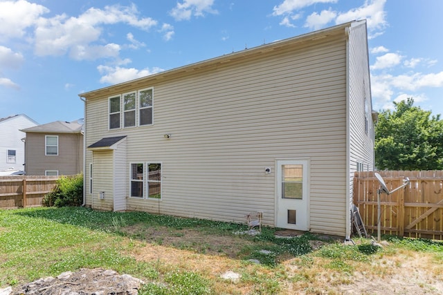 rear view of house featuring a fenced backyard and a yard
