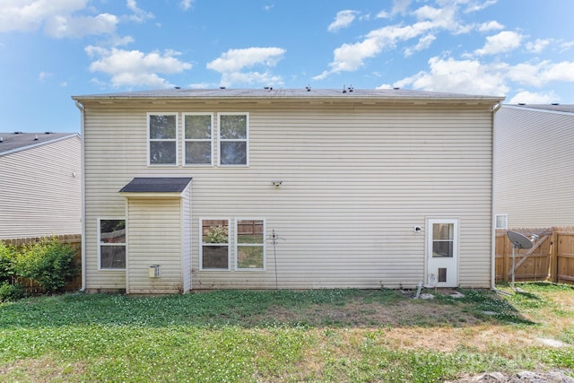 rear view of property with a yard and fence