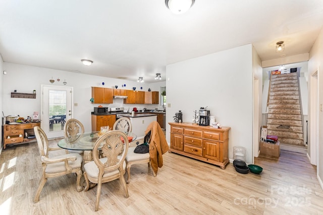 dining space with stairs, light wood-style floors, and a healthy amount of sunlight