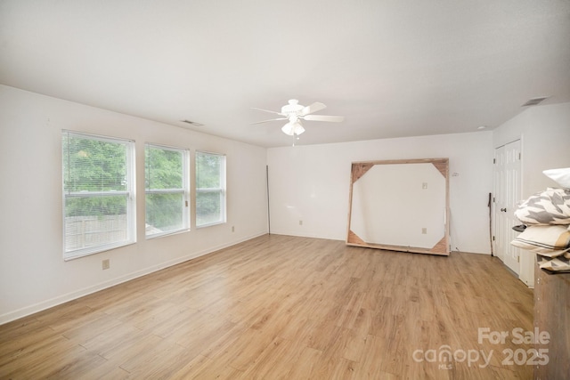 empty room featuring light wood finished floors, visible vents, baseboards, and a ceiling fan