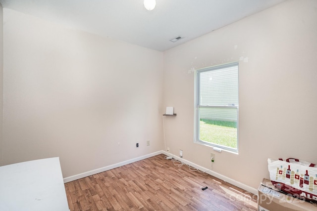 spare room with baseboards and light wood-type flooring