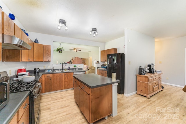 kitchen with under cabinet range hood, dark countertops, a sink, and black appliances
