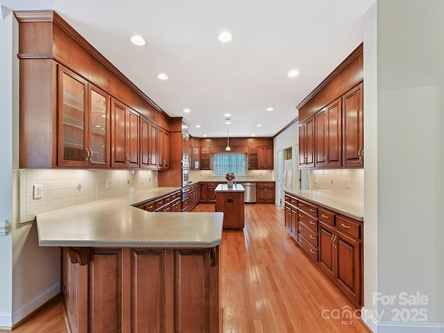 kitchen with a peninsula, light wood-style floors, glass insert cabinets, and stainless steel dishwasher