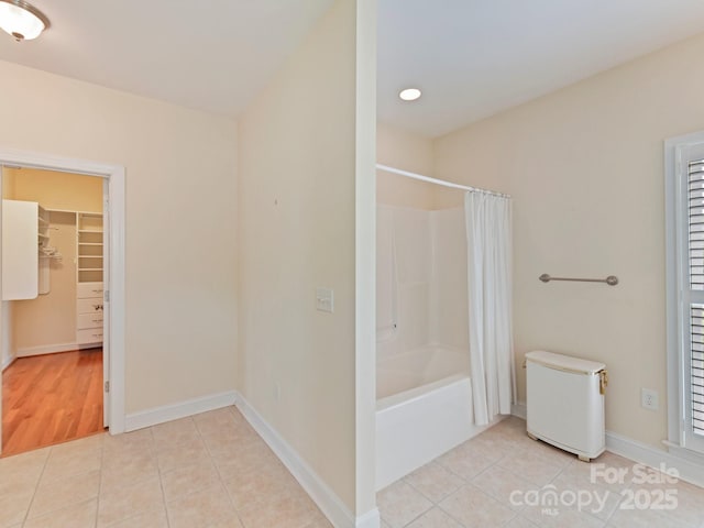 bathroom featuring tile patterned flooring, shower / bathtub combination with curtain, a walk in closet, and baseboards