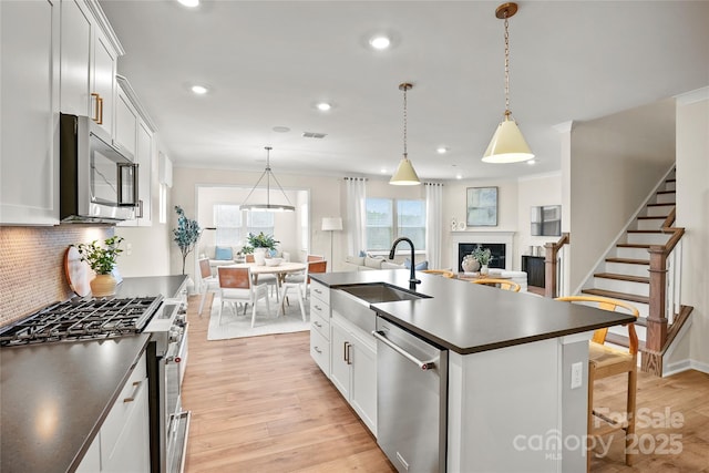 13709 Roderick Dr Unit 193, Huntersville, NC 28078 - kitchen featuring appliances with stainless steel finishes, dark countertops, decorative backsplash, light wood finished floors, and a sink