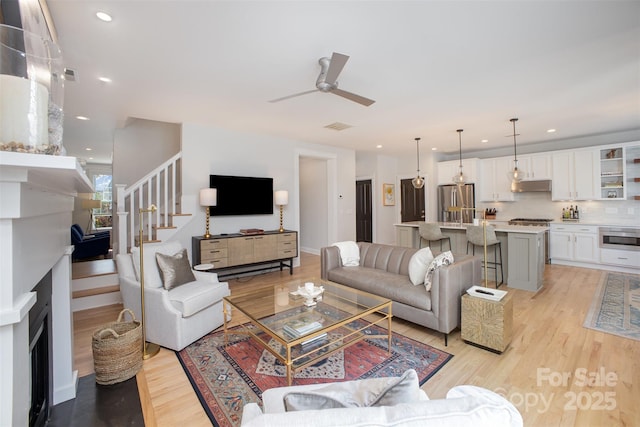 107 Iris Meadow Dr, Mooresville, NC 28115 - living room with stairs, a fireplace, light wood-style floors, and a ceiling fan