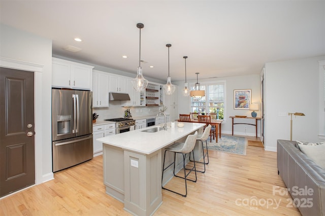 107 Iris Meadow Dr, Mooresville, NC 28115 - kitchen featuring light countertops, a sink, a breakfast bar area, appliances with stainless steel finishes, and light wood-style floors