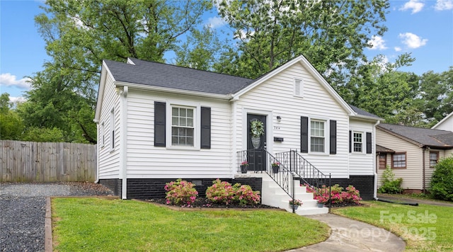 bungalow-style home with fence, roof with shingles, crawl space, and a front lawn