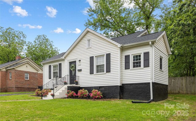 view of front facade featuring fence, a front yard, and a shingled roof