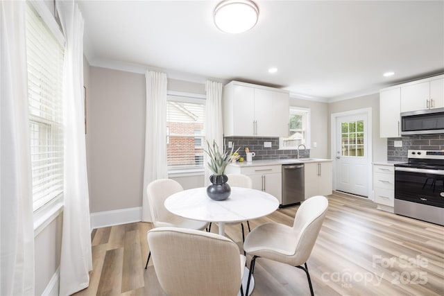 kitchen featuring crown molding, appliances with stainless steel finishes, light countertops, and decorative backsplash