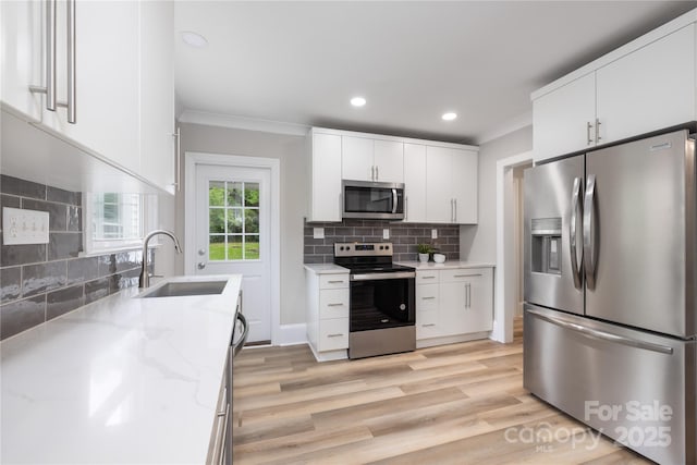 kitchen featuring recessed lighting, a sink, stainless steel appliances, crown molding, and backsplash