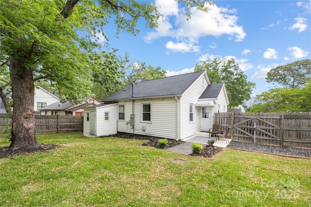 rear view of house featuring a storage shed, a yard, a patio, and a fenced backyard