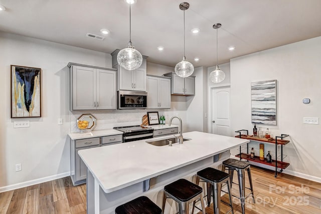 8038 Downy Oak Ln, Charlotte, NC 28269 - kitchen featuring gray cabinets, a sink, a breakfast bar area, appliances with stainless steel finishes, and visible vents