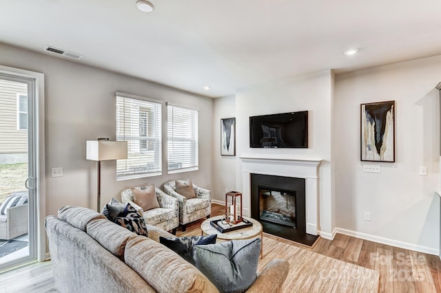 8038 Downy Oak Ln, Charlotte, NC 28269 - living area featuring wood finished floors, a glass covered fireplace, baseboards, visible vents, and recessed lighting