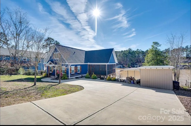 exterior space with a sunroom, an outbuilding, and a front lawn