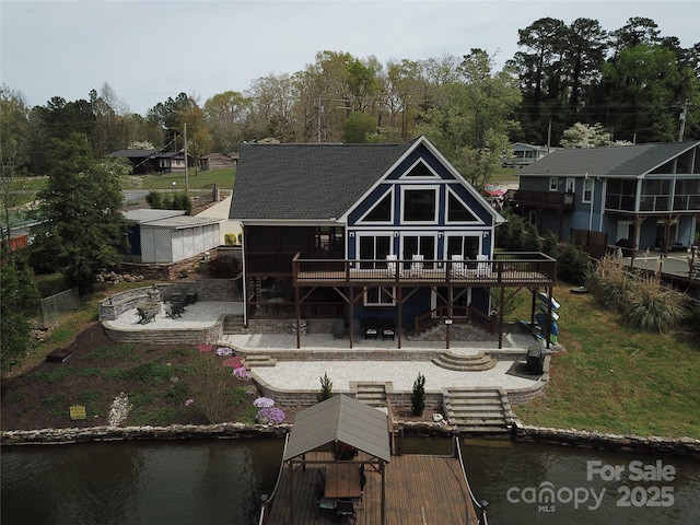 rear view of house with a deck with water view, stairway, a fire pit, and a patio