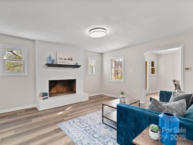 507 N Fork Rd, Black Mountain, NC 28711 - living room featuring healthy amount of natural light, a brick fireplace, wood finished floors, baseboards, and a textured ceiling