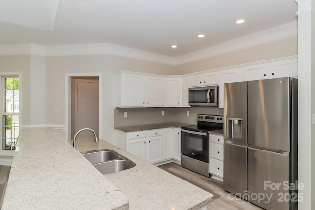 kitchen featuring a sink, appliances with stainless steel finishes, white cabinetry, and crown molding