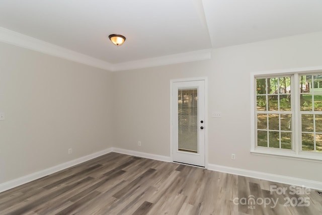 unfurnished room featuring baseboards, crown molding, and wood finished floors