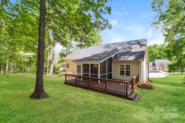 rear view of house featuring a yard, roof with shingles, and a sunroom