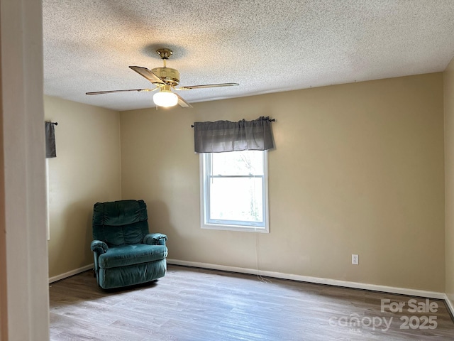 unfurnished room featuring a textured ceiling, baseboards, a ceiling fan, and wood finished floors