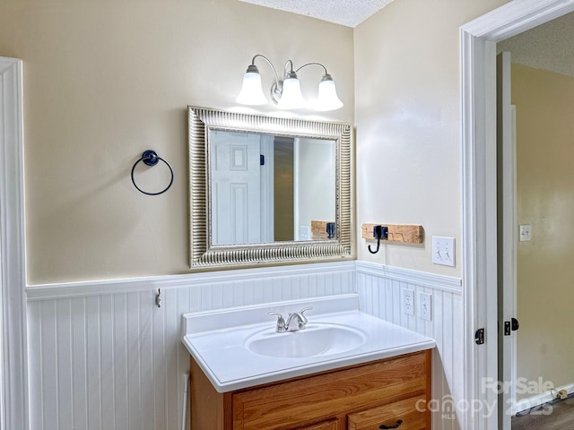 bathroom featuring a textured ceiling, wainscoting, and vanity