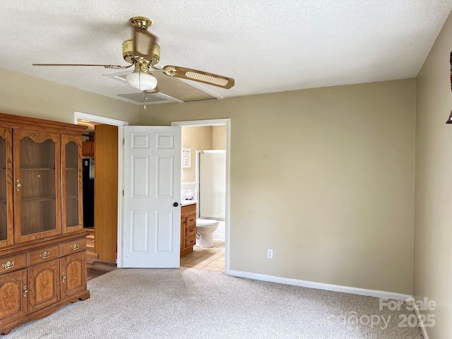 unfurnished bedroom with baseboards, ensuite bath, light carpet, and a textured ceiling