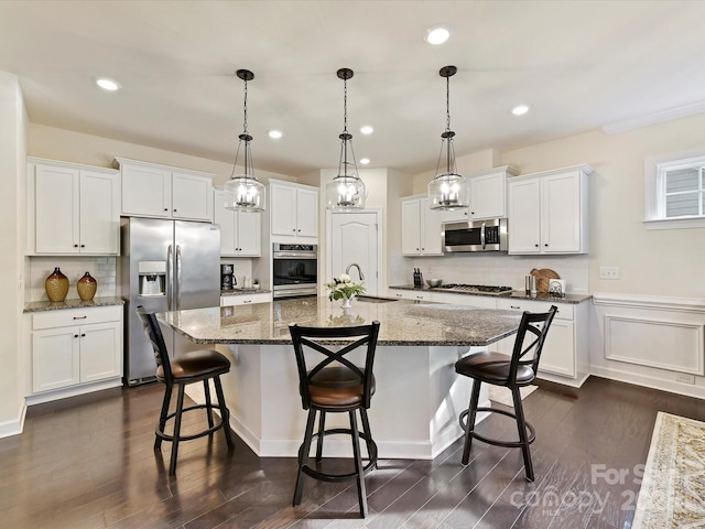 kitchen with appliances with stainless steel finishes, a breakfast bar area, white cabinetry, and a sink