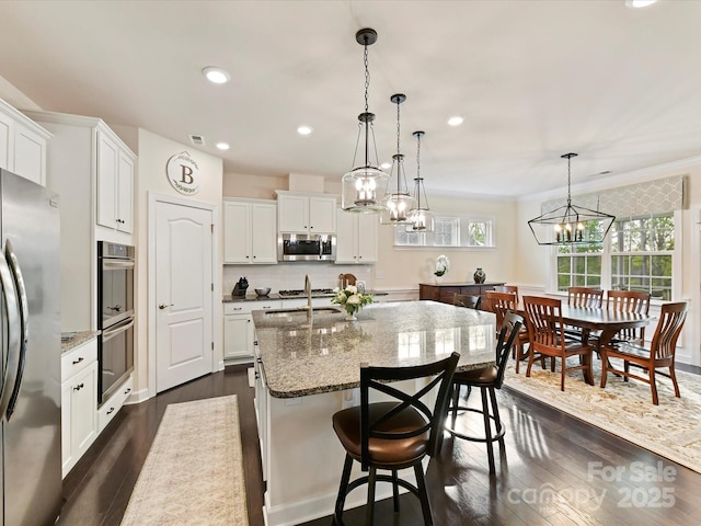 kitchen with light stone counters, a sink, a chandelier, and appliances with stainless steel finishes