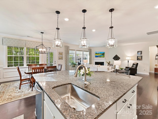 kitchen with visible vents, stainless steel dishwasher, a sink, dark wood-type flooring, and a notable chandelier