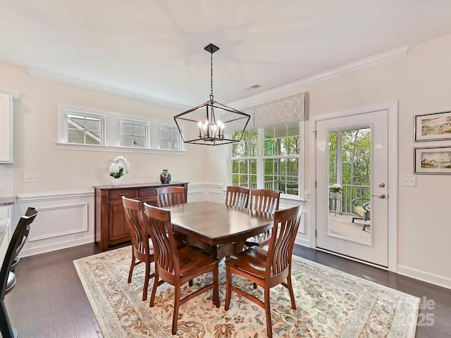 dining area with dark wood-style floors, wainscoting, visible vents, a chandelier, and crown molding