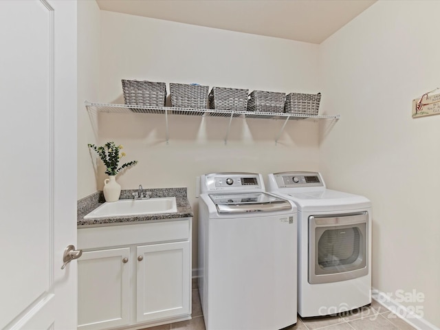 clothes washing area featuring a sink, light tile patterned floors, cabinet space, washing machine and dryer, and baseboards